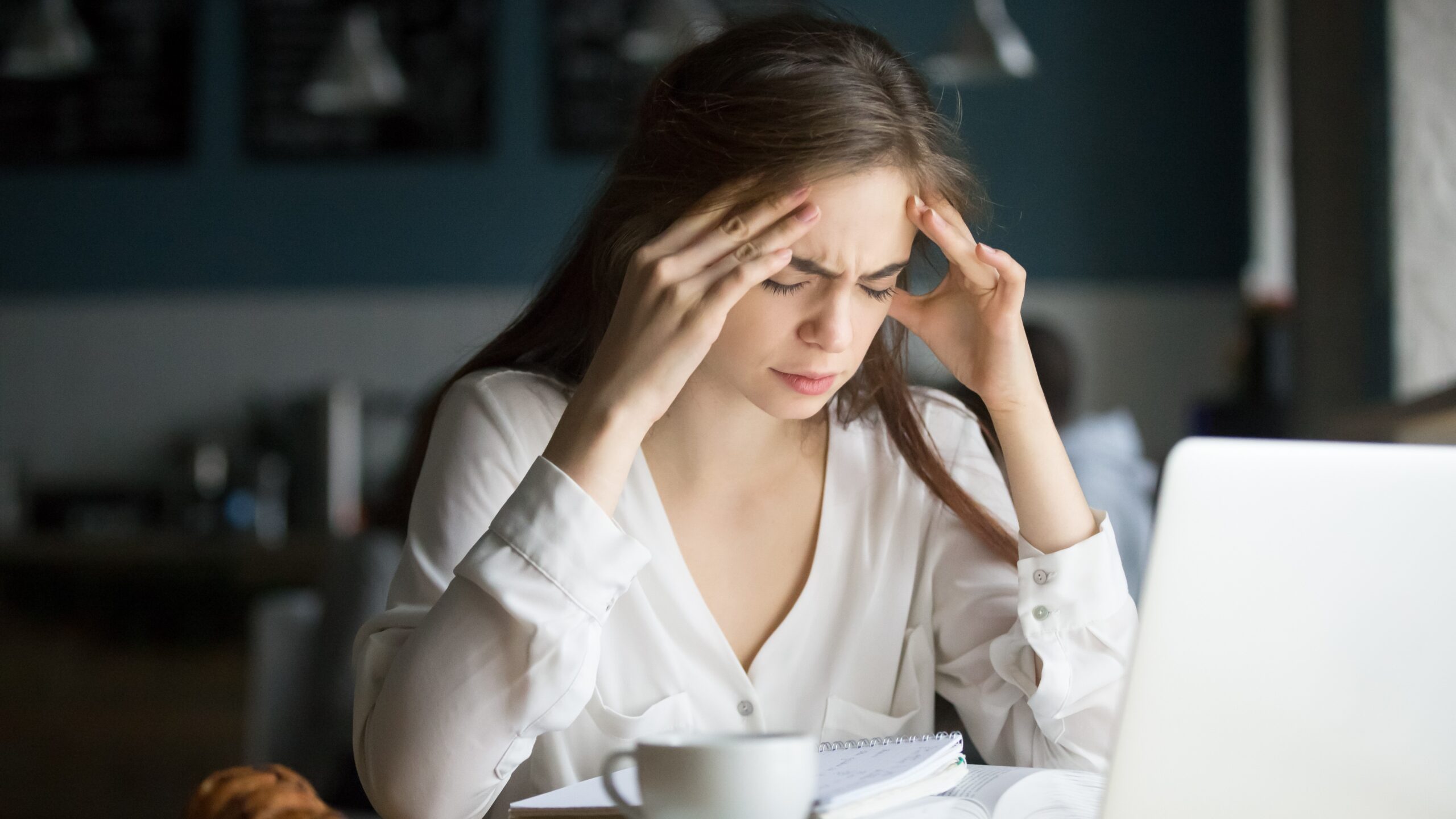 Nervous stressed female student feeling headache studying in cafe